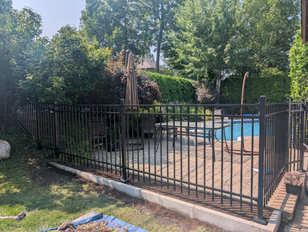 Clôture en aluminium ornemental noir autour d'un patio en pavé avec piscine